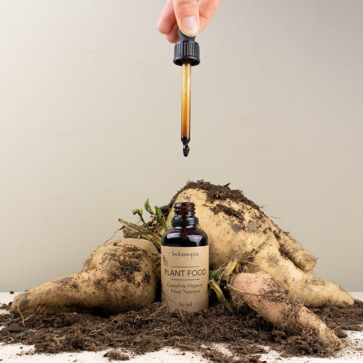 Botanopia organische plantenvoeding in een bruin flesje met pipetje met op de achtergrond wortels