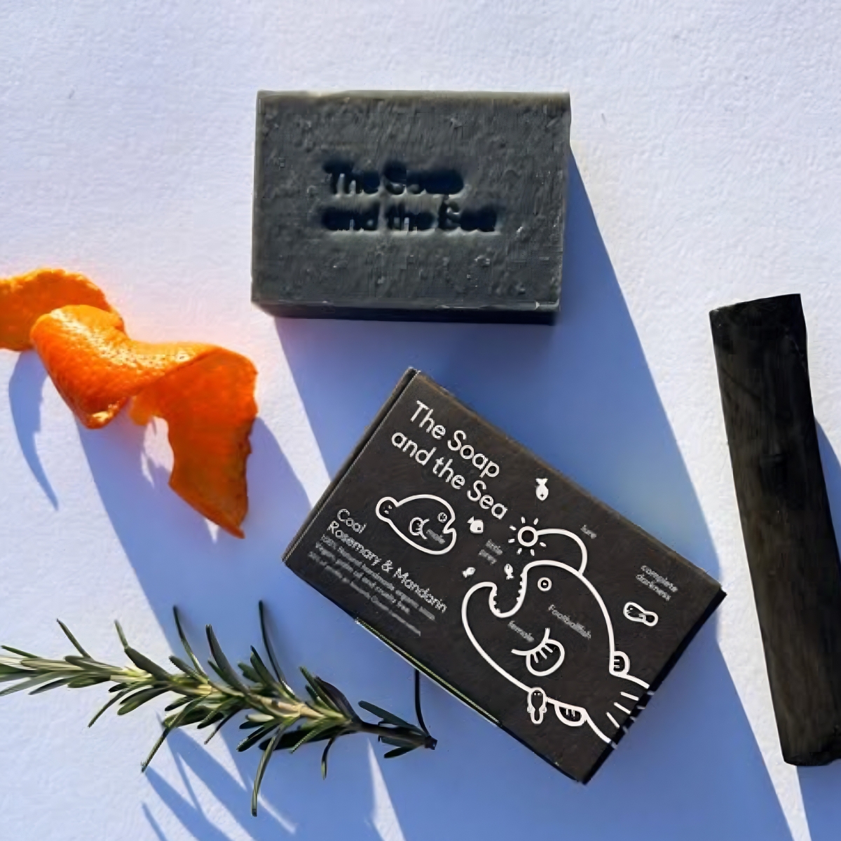 The Soap and The Sea Mmandarijn, rozemarijn en houtskool zeep met ingrediënten afgebeeld
